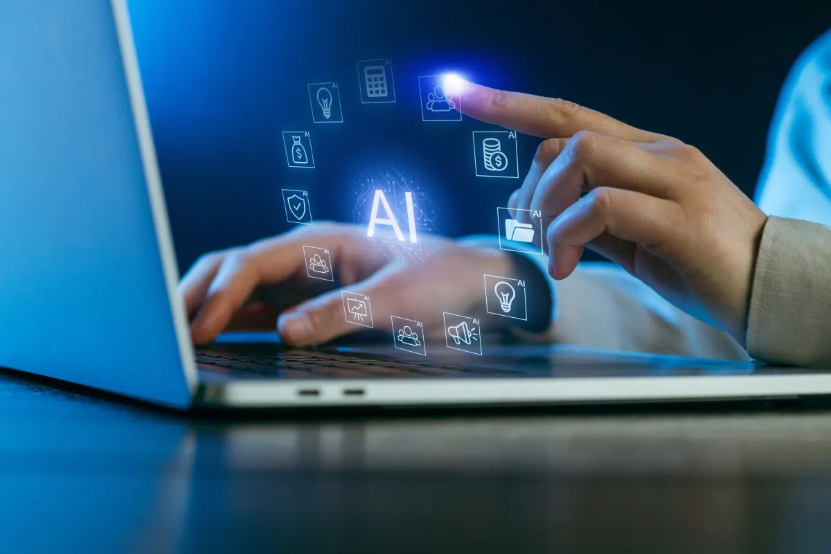 Mãos no notebook com ícones de inteligência artificial flutuando sobre o teclado