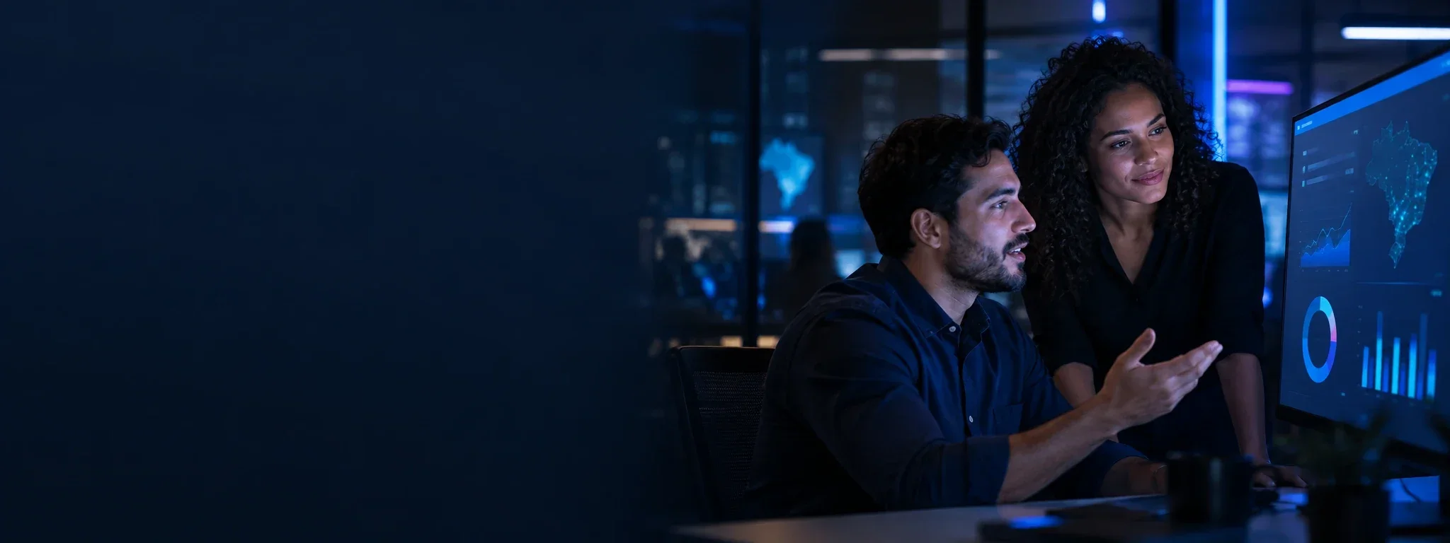Dois profissionais analisam juntos um painel de indicadores no monitor